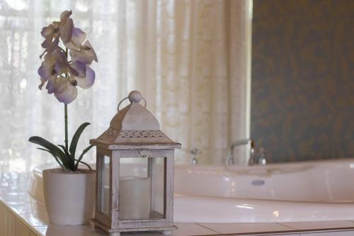 a bathroom with a lantern and a vase with flowers at Rose Petal Cottage Quaint Studio In Ballarat in Ballarat