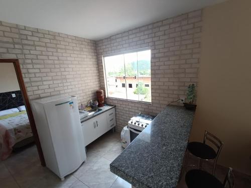 a kitchen with a white refrigerator and a window at pousada Montanhez ap3 in Alto Caparao