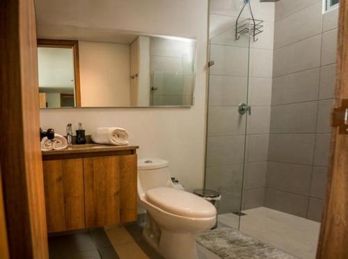 a bathroom with a toilet and a shower with a mirror at Lindo Apartamento en rodadero sur in Gaira