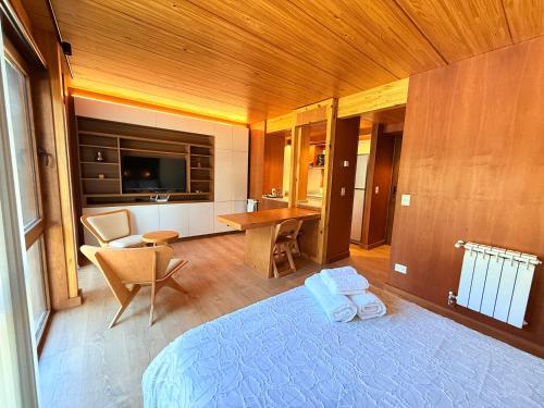 a bedroom with a bed and a desk and a television at Hermoso monoambiente en el centro de SMA, muy cálido y modernoso V407 in San Martín de los Andes