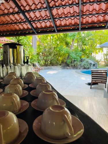 a row of teapots on plates on a table at Calala Lodge in Cabuya
