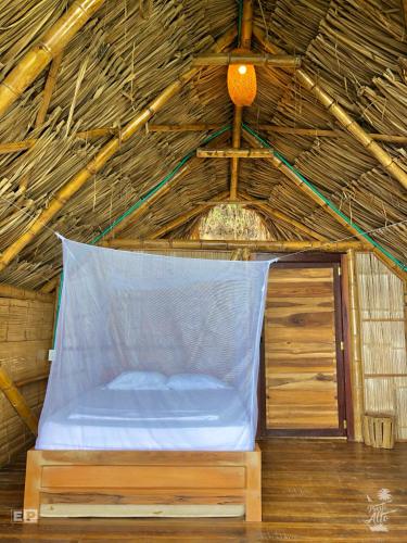 a bed in a straw hut with a net at Puerto Alto Hostel in Santa Marta