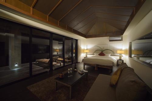 a bedroom with a bed and a couch and a table at Mukaka Villa in Nakijin