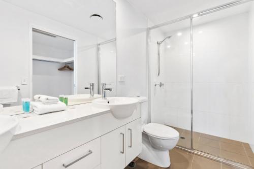 a white bathroom with a sink and a toilet at Harbour Quays Apartments in Gold Coast