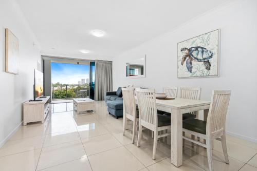 a dining room and living room with a table and chairs at Harbour Quays Apartments in Gold Coast