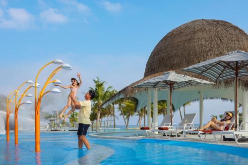 a man and a woman jumping into a pool at a resort at Centara Mirage Lagoon Maldives in Nakachchafushi