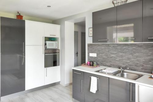 une cuisine avec des armoires blanches et un évier dans l'établissement Charmante Maison à Fort-Moville avec Terrasse Privée, à Fort-Moville