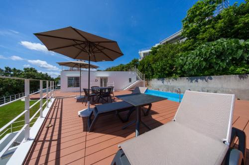 a patio with a table and chairs and an umbrella at クリスタルヴィラ南城 in Azama
