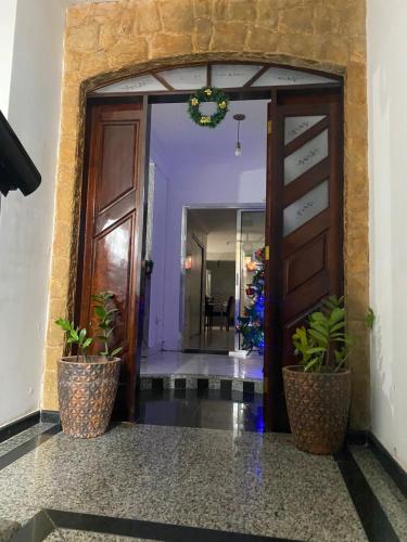 a hallway with a door and two potted plants at Hostel ANPRADO 6 in Guarulhos