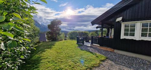 een huis met een grasveld naast een gebouw bij Panorama Cabin - Stunning Mountain Views and Outdoor Jacuzzi Option in Bjorli