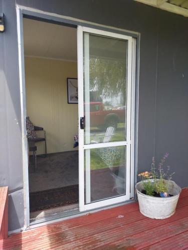 an open door to a porch with a potted plant at Waitomo Farmstay - Cabin 3 and 4 in Waitomo Caves