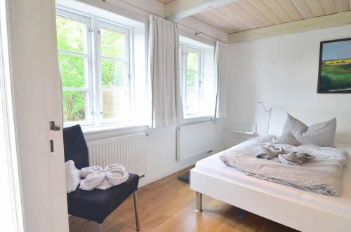 une chambre avec un lit, une chaise et des fenêtres dans l'établissement Wohnung-1, à Nebel