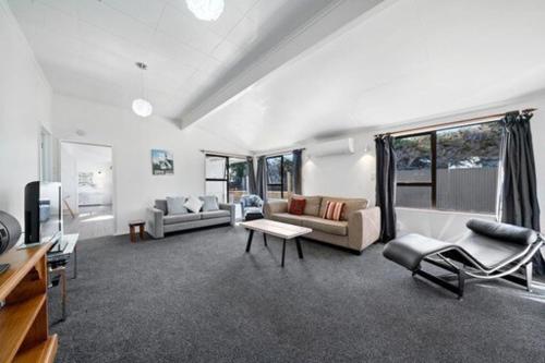 a large living room with couches and a tv at Seashell cottage in Waitarere