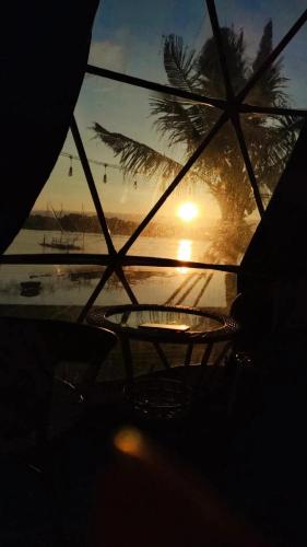 a view of a sunset through a window with a table at อินทนนท์แคมป์ปิ้ง เขื่อนสิรินธร in Sirindhorn