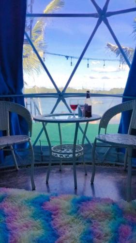 a table with a glass of wine and two chairs at อินทนนท์แคมป์ปิ้ง เขื่อนสิรินธร in Sirindhorn
