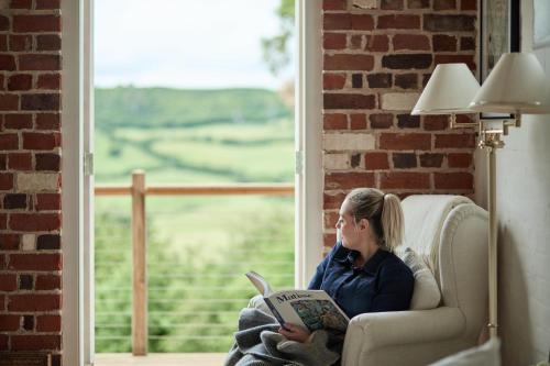 a woman sitting in a chair reading a book next to a window at Harland Rise Chapel Circa 1830 in Evandale