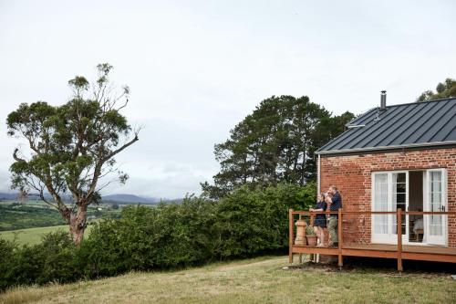 a couple standing on the deck of a tiny house at Harland Rise Chapel Circa 1830 in Evandale