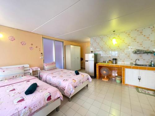 a bedroom with two beds and a kitchen with a refrigerator at Impact Arena C3 Milo in Nonthaburi