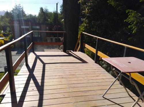 a wooden walkway with a bench and a table on it at Pueblo Patagonia in Villa La Angostura