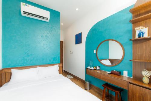 a bedroom with a blue wall with a bed and a mirror at The BackPacker Hotel in Da Nang