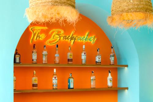 a display of bottles of alcohol on an orange wall at The BackPacker Hotel in Da Nang