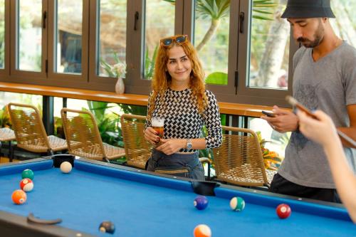 a group of people standing around a pool table at The BackPacker Hotel in Da Nang