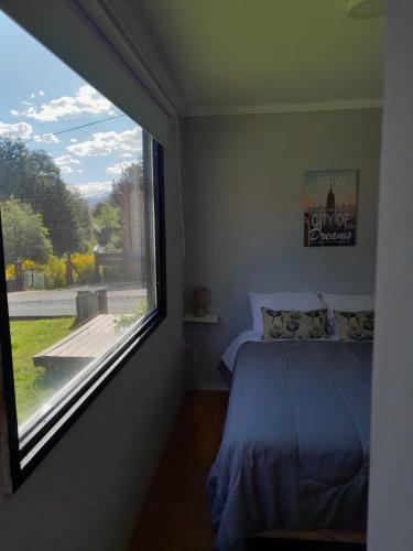 a bedroom with a bed and a large window at Pueblo Patagonia in Villa La Angostura