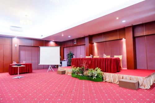 a conference room with red tables and a white screen at Horison Altama Pandeglang in Pandegelang