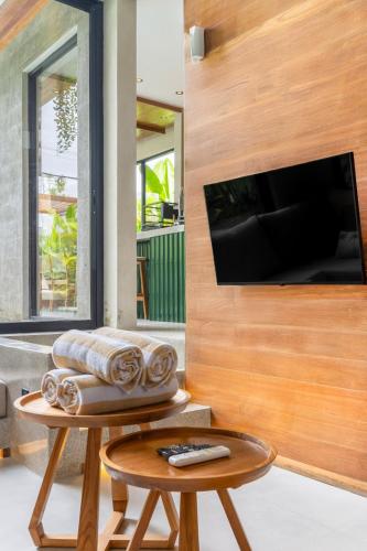 a living room with a table and a tv at Nanna Villa Unit 2 by Betterplace in Tumbak Bayuh