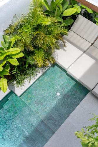 a swimming pool in a garden with plants at Nanna Villa Unit 2 by Betterplace in Tumbak Bayuh