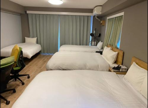 ein Hotelzimmer mit zwei Betten und einem Stuhl in der Unterkunft Shiki no Sai Asakusa in Tokio