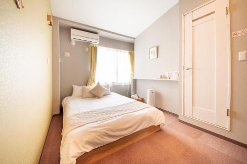 a small room with a bed with a window at Hotel Neiraku in Nara