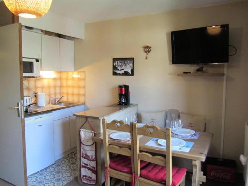 une petite cuisine avec une table et une télévision murale dans l'établissement Résidence Combettes - Combettes E288 MAE-5071, aux Contamines-Montjoie