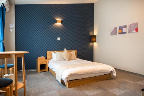 a bedroom with a bed and a blue wall at Hotel Neiraku in Nara