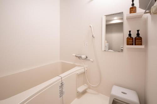 a white bathroom with a shower and a sink at Hotel Neiraku in Nara