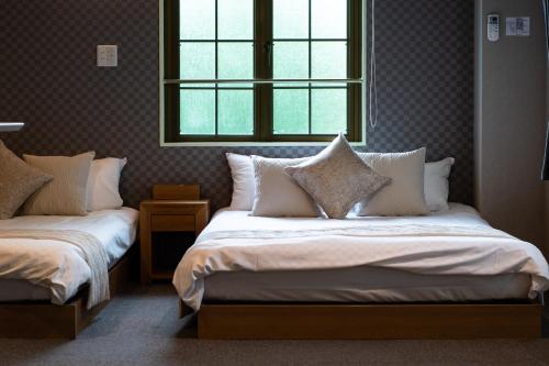 a bedroom with two beds and a window at Hotel Neiraku in Nara