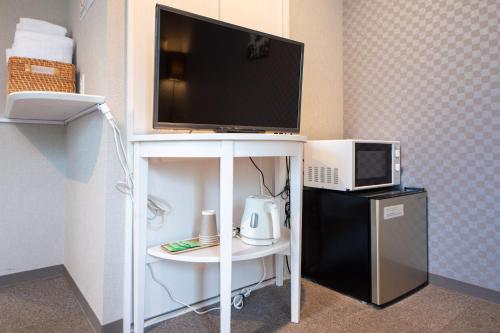 a television on a white stand with a small refrigerator at Hotel Neiraku in Nara