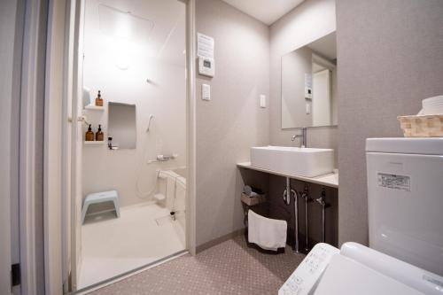 a white bathroom with a sink and a toilet at Hotel Neiraku in Nara