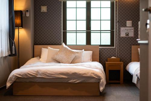 a bedroom with a bed with pillows and a window at Hotel Neiraku in Nara