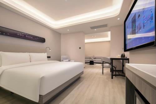 Un dormitorio con una cama blanca y un televisor de pantalla plana. en Atour X Hotel Wuhan Wuhan Yellow Crane Tower Yangtze River Bridge, en Han-yang-hsien