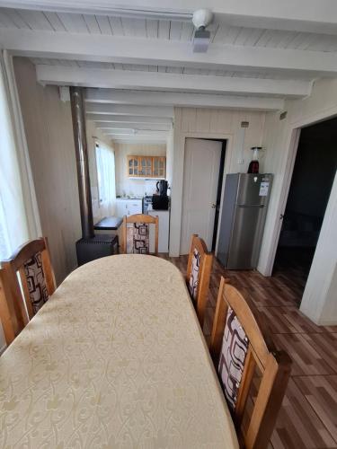 a dining room with a table and chairs and a kitchen at Cabañas Eben Ezer in Queule