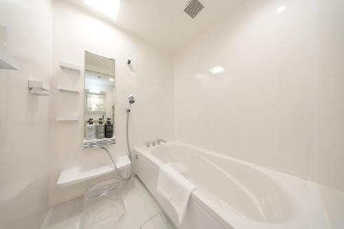 a white bathroom with a tub and a sink at クリスタルヴィラ南城 in Azama