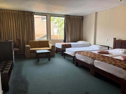 a hotel room with two beds and a chair at Hotel Janaki in Colombo