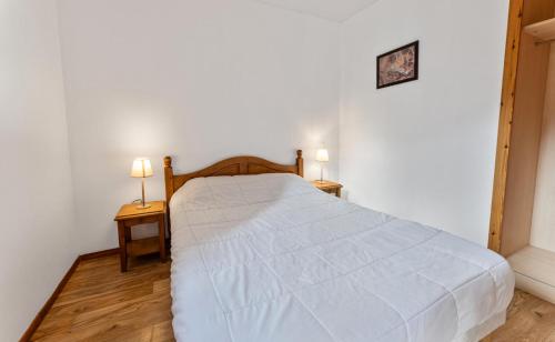 une chambre avec un lit blanc avec deux tables de nuit dans l'établissement Résidence Les Hauts De Preclaux - 2 pièces au coeur des Orres 1800 MAE-0751, aux Orres