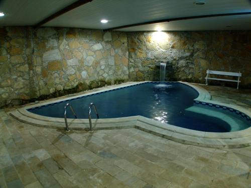 a large swimming pool with a bench in a stone wall at Pousada Berço da Liberdade in Tiradentes