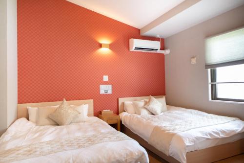 two beds in a room with red wallpaper at Hotel Neiraku in Nara