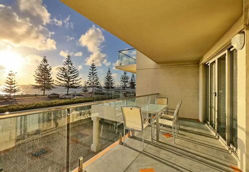 a glass balcony with a table and chairs on it at Beachside at Scarborough in Perth