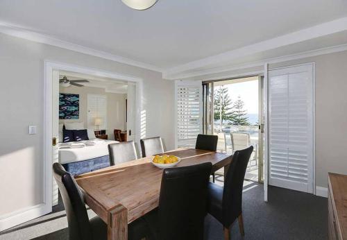 a dining room with a table and chairs and a bedroom at Beachside at Scarborough in Perth