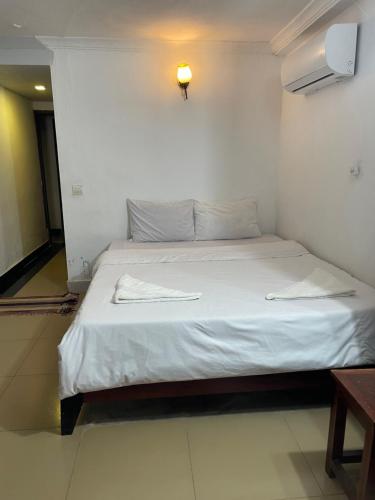 The ream beach hostel في Phsar Ream: غرفة نوم بسرير ذو شراشف بيضاء واضاءة