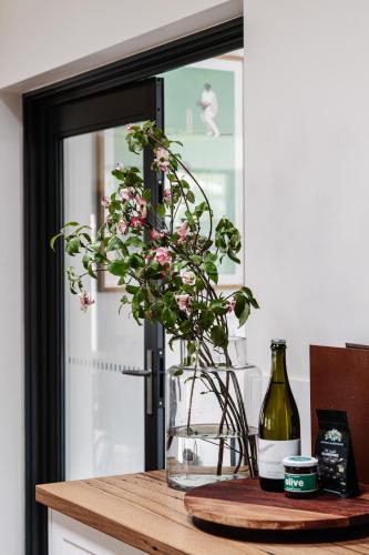 a vase of flowers on a counter with a bottle of wine at Athlete's Retreat - 21A Service Street in Porepunkah